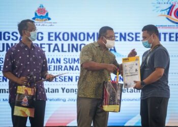 AMIRUDIN Shari menyampaikan lesen pasar kepada salah seorang peniaga yang turut disaksikan oleh Datuk Bandar Petaling Jaya, Mohamad Azhan Md. Amir (kiri) sempena Program Meransang Ekonomi Mensejahtera Komuniti Petaling Jaya yang berlansung di Laman MBPJ, Jalan Yong Shook Lin di sini, hari ini. -UTUSAN/MUHAMAD IQBAL ROSLI