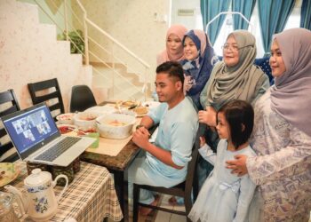 ROAYAHA Ali (berdiri, dua kanan) bersama beberapa ahli keluarganya yang tinggal bersama hanya menyambut Hari Raya Aidilfitri di rumah sambil berbual bersama sanak-saudara melalui panggilan dalam talian aplikasi Zoom di Taman Kajang Impian. - UTUSAN/AMIR KHALID
