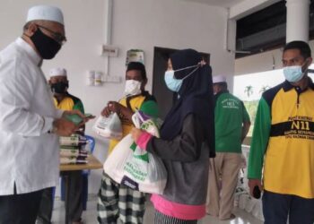 RAZMAN Zakaria (kiri) menyampaikan sumbangan barangan makanan kepada asnaf di Lembah Beriah, Bagan Serai hari ini. - FOTO/WAT KAMAL ABAS