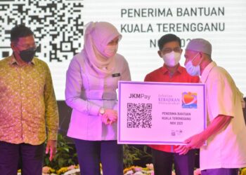 RINA Mohd. Harun (dua, dari kiri) menyampaikan replika kad JKMPay kepada seorang penerima dalam program pembayaran bantuan kewangan tanpa tunai Jabatan Kebajikan Masyarakat (JKM) di Taman Sinar Harapan di Kuala Terengganu, hari ini. - UTUSAN/PUQTRA HAIRRY ROSLI