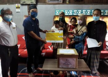 NUR Shahida Saidi (tengah) menerima cek Faedah Pengurusan Mayat Perkeso yang disampaikan oleh Abdul Yunus Jamahri di Kampung Parit Mat Ali, Kuala Kurau dekat Parit Buntar, Perak,  hari ini. - UTUSAN/WAT KAMAL ABAS