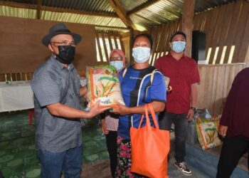 Ronald Kiandee (kiri) menyampaikan bantuan bakul makanan kepada salah seorang penduduk Kampung Maidan Paitan, Sabah hari ini
