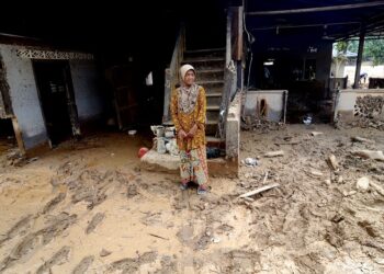 Che Liah Ramli, 64, kembali semula ke rumahnya di Kampung Lata Celak yang juga teruk dilanda banjir lumpur berpunca daripada kepala air dari Gunung Inas Isnin lalu. – UTUSAN/IQBAL HAMDAN