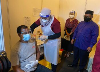 MOHD. Khairuddin Aman Razali (kanan) melihat salah seorang pekerja industri menerima suntikan vaksin melalui Program PIKAS di PPV SKT Banquet Hall 68, Jalan Sungai Abong, Muar, Johor. -UTUSAN/NUR ALINA HASSAN