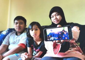 NURSAZZEY Shazmika Mazlan (kanan) bersama Mohd.Irfan (kiri) dan Nurmia Syazmira (tengah) berkongsi satu-satunya gambar keluarga mereka yang masih berada dalam simpanan ketika ditemui di Putatan, semalam.