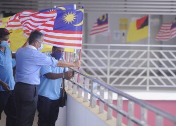 SEREMBAN 12 Ogos - AHLI Dewan Undangan Negeri (ADUN) Lobak, Chew Seh Yong membantu petugas Majlis Bandaraya Seremban (MBS), memasang Jalur Gemilang di bangunan Pasar Besar Seremban, semalam.-UTUSAN/MOHD. SHAHJEHAN MAAMIN.