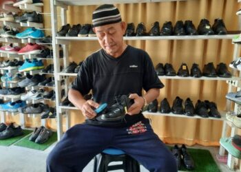 RAZALI Mohammad membersihkan kasut kulit terpakai yang dijual di kedainya di Pekan Langgar, Alor Setar, Kedah. - UTUSAN/ MOHD. RIFAAT ABD. HAMID