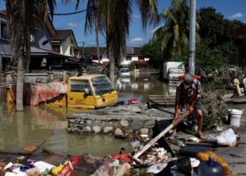 MANGSA banjir membersihkan halaman kediaman mereka, selepas banjir  melanda Seksyen 25 Sri Muda, Shah Alam, Selangor, Sabtu lalu. -  UTUSAN/ZULFADHLI ZAKI
