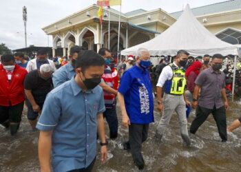 ISMAIL Sabri Yaakob meredah banjir ketika melawat mangsa-mangsa yang ditempatkan di pusat pemindahan sementara (PPS) di Sekolah Kebangsaan Telok Gong. - FOTO/JABATAN PERDANA MENTERI