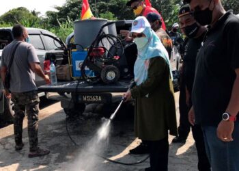 RODZIAH Ismail menyembur cecair antibakteria dalam Program Bio-Remediasi Selangor Pasca Banjir di Padang Jawa, Shah Alam, Selangor semalam. - UTUSAN / MOHAMAD NAUFAL MOHAMAD IDRIS