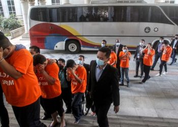 SERAMAI 23 suspek termasuk Pegawai Jabatan Imigresen Malaysia dikawal Pegawai Suruhanjaya Pencegahan Rasuah Malaysia untuk perintah tahanan reman kes pemalsuan cap pasport warga asing di Mahkamah Majistret Putrajaya, semalam. - UTUSAN/FAISOL MUSTAFA