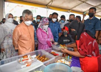 AL-SULTAN Abdullah Ri'ayatuddin Al-Mustafa Billah Shah (kiri) bersama Tunku Hajah Azizah Aminah Maimunah Iskandariah (tiga dari kiri) menyantuni peniaga keria gula Melaka ketika berkenan melawat Bazar Ramadan Peringgit sempena lawatan ke Melaka. - FOTO/RASUL AZLI SAMAD