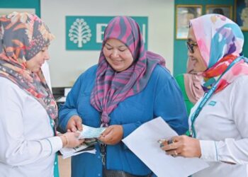 NORZILAWATI Jusoh@Mohd. Zain (tengah) gembira menerima STR daripada pegawai Bank Simpanan Nasional (BSN) di Cawangan Kuala Nerus di Batu Enam, Kuala Nerus, Terengganu, baru-baru ini.