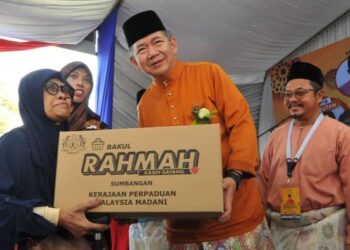 SALAHUDDIN Ayub menyampaikan sumbangan kepada salah seorang asnaf sempena Rumah Terbuka Aidilfitri Ahli Parlimen Pulai di Taman Rekreasi Taman Uda Utama, Johor Bahru, hari ini. - UTUSAN/RAJA JAAFAR ALI