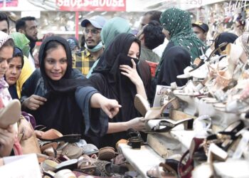 SEKUMPULAN wanita memilih kasut yang dijual di pasar sewaktu membeli-belah menjelang Hari Raya Aidilfitri di Karachi, Pakistan, semalam. – AFP