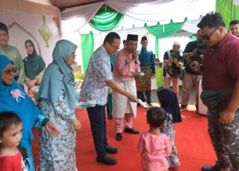 AHMAD Samsuri Mokhtar menyampaikan sumbangan  duit raya kepada kanak-kanak dalam sambutan Hari Raya DUN Rhu Rendang di Pantai Peranginan Kelulut, Marang, Terengganu, semalam. – UTUSAN/PUQTRA HAIRRY ROSLI