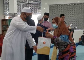 MUHAMMAD Sanusi Md. Nor menyerahkan sumbangan kepada salah seorang penduduk pada majlis penyampaian sumbangan dan berbuka puasa peringkat daerah Langkawi di Masjid Aisyah, Langkawi, semalam. - FOTO/NUR AMALINA AZMAN