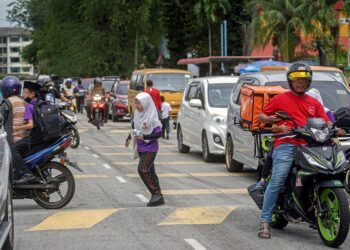 Seorang  pelajar melintas jalan tanpa pengawasan ketika lalu lintas sesak di hadapan Sekolah Kebangsaan Bandar Sunway di Petaling Jaya semalam. – UTUSAN/SHIDDIEQIIN ZON