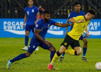 PEMAIN Malaysia, Stuart Wilkin (kanan) bersaing dengan Anumanthan Kumar dari Singapura dalam aksi Piala AFF di Stadium Nasional, Bukit Jalil semalam. - UTUSAN/MUHAMAD IQBAL ROSLI/