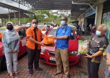 SUHAIZAN Kaiat (dua dari kiri) menyampaikan sumbangan barangan keperluan harian kepada pemandu teksi di Pasaraya A-Mart Kempas, Johor Bahru.