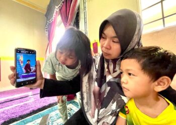 SITI Rohani Makanal bersama anak-anaknya menatap gambar  arwah Muhammad Amir Faris yang mati lemas ketika ditemui di Kampung Katong, Arau, Perlis.- MINGGUAN/NAZLINA NADZARI
