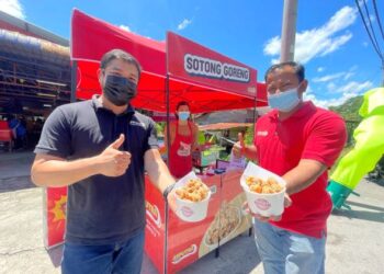 MOHD. Fahimie Hassan (kiri) bersama abangnya, Mohd. Hafirzi menunjukkan sotong goreng tepung yang dijual di kiosk mereka di Arau, Perlis, semalam. – UTUSAN/NAZLINA NADZARI