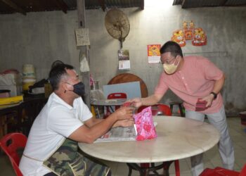 NGA Kor Ming (kanan) memberi angpau kepada peniaga pada program pemberian buah limau serta angpau sempena Tahun Baru Cina di Pasar Awam Buntong, Ipoh, Perak,  hari ini. - UTUSAN/ZULFACHRI ZULKIFLI