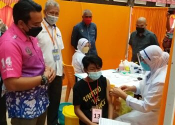 AHMAD Saidi Mohamad Daud (kiri) melihat pelajar yang menerima suntikan vaksin Covid-19  di SMKA Sultan Azlan Shah, Seri Iskandar dekat Parit, Perak,  hari ini.