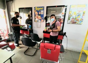 MOHD. Azrulnizam Azran (kiri) dan pembantunya, Mohd. Rafiq Ishak mengemas kedai gunting rambut walaupun belum dibenarkan beroperasi di Taman Rambai Utama, Melaka. - UTUSAN/AMRAN MULUP