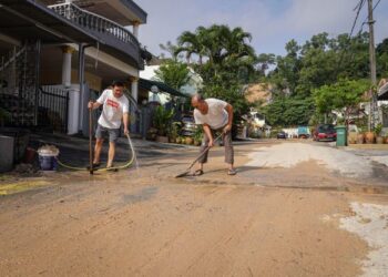 PARA penduduk Taman Mega Jaya membersihkan persekitaran rumah mereka yang terkesan akibat banjir lumpur.-UTUSAN/FARIZ RUSADIO