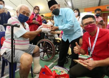 TOSRIN Jarvanthi (tengah) memberikan sumbangan kepada salah seorang penerima bantuan Tahun Baru Cina di Dewan Raya Putra, Kulai di Johor.