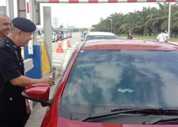 SYED Muhd. Naguib Syed Mohd (kiri) bersama Chong Boon Khim menyerahkan cenderahati kepada pengguna WCE di Plaza Tol Sitiawan Utara dekat Lumut  hari ini. - UTUSAN