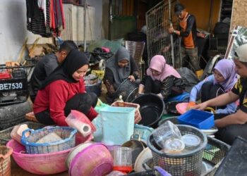 ANGGOTA sukarelawan bergotong-royong membersihkan barangan milik penduduk yang ditenggelami air di Kampung Durian Mentangau, Dungun, Terengganu. - FOTO/PUQTRA HAIRRY ROSLI