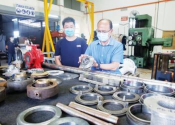 Mohd. Shukri Htam (kanan) menunjukkan komponen besi yang dihasilkan di kilang miliknya di Telok Kalong, baru-baru ini.  – UTUSAN/PUQTRA HAIRRY