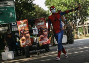 Peniaga Teh Avengers, Mohd.Zahir Mohd.Sofee (kiri)  memakai kostum Spiderman memanggil pelanggan yang lalu-lalang
singgah di tempatnya berniaga di Seksyen 20 Shah Alam Selangor. -UTUSAN/ZULFADLI MOHD.ZAKI