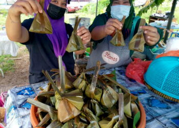 Shahida Mahamad Shirie (kiri) menunjukkan kuih tepung bungkus yang dijualnya pada harga RM1 di Taman Laksamana, Segamat, Johor. - UTUSAN/ FARAHWAHIDA AHMAD