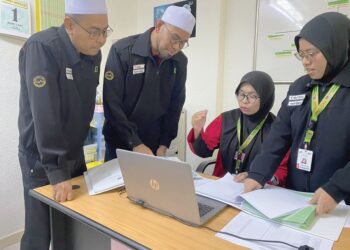 FAZLI Ahmad (kiri) dan Muhammad Faizal Maarof mendengar penerangan mengenai maklumat pesakit ketika bertugas di pusat perubatan TH di Tanah Suci.