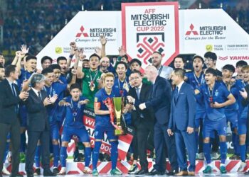 Theerathon Bunmathan (tengah, kiri) memegang Piala AFF selepas mengetuai Thailand menumpaskan Vietnam dalam perlawanan akhir di Stadium Thammasat, Bangkok kelmarin. – AFP