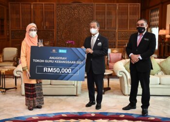 MUHYIDDIN Yassin menyampaikan Anugerah Tokoh Guru Kebangsaan Tahun 2021 kepada Noorizan Mohamed di Putrajaya, semalam. - GAMBAR: JABATAN PERDANA MENTERI