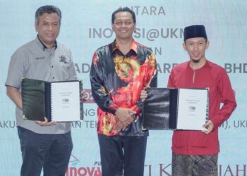 Dr. Wan Kamal Mujani (tengah) menyaksikan pertukaran dokumen antara Mohammad Munzir Aminuddin (kanan) dengan Ir. Dr. Abdul Wahab Mohammad  pada Majlis Penyerahan Dokumen Perjanjian Perlesenan antara Inovasi@ KM dengan Siti Khadijah Apparel Sdn. Bhd. di  UKM, Bangi.