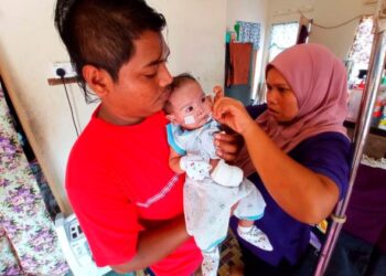 MOHD. Suhaimi Jasmin bersama isterinya, Asfanizan Othman mendukung Nur Qaira yang kini bergantung pada mesin oksigen ekoran mengalami masalah saluran nafas sempit di Taman Sinar Sedili, Tanjung Sedili, Kota Tinggi, Johor. - FOTO/MASTURAH SURADI