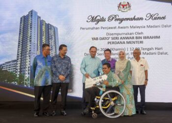 Anwar Ibrahim menyerahkan replika  kunci kepada salah seorang pembeli Projek Perumahan Penjawat Awam Malaysia (PPAM) Dalur Madani di Presint 18, Putrajaya, semalam. - UTUSAN/FAISOL MUSTAFA