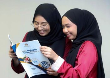 KAKITANGAN Unit Kesejahteraan Bahagian Perangkaan Tenaga Manusia dan Sosial, Nor Izzati Mustaffar (kanan) dan Nursyazwani Malik melihat buku Laporan Indeks Kebahagian Rakyat Malaysia (MHI) 2021 di Jabatan Perangkaan Malaysia, Putrajaya. - UTUSAN/FAISOL MUSTAFA
