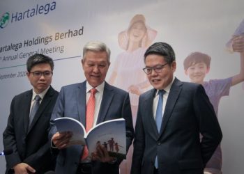 KUAN Kam Hon (tengah) dan Kuan Mun Leong (kanan) melihat buku laporan tahunan Hartalega di Kuala Lumpur, semalam.