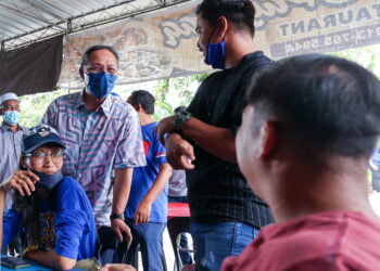 HASNI Mohammad (kiri) bertukar pandangan dengan anak muda ketika singgah ke sebuah warung di Parit Mekuaseng di Benut, Pontian, Johor.