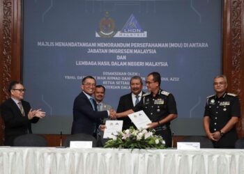 KETUA Setiausaha Kementerian Dalam Negeri (KDN) Datuk Wan Ahmad Dahlan Abdul Aziz (tiga dari kanan) menyaksikan pertukaran MoU antara Khairul Dzaimee Daud (dua dari kanan) dengan Mohd. Nizom Sairi di Cyberjaya, hari ini. - UTUSAN/FAISOL MUSTAFA