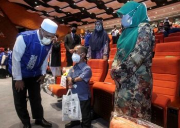 IDRIS Ahmad beramah mesra bersama penerima sumbangan pada Majlis Penyampaian Sumbangan Musa'adah kepada warga agensi Jabatan Perdana Menteri (Hal Ehwal Agama) yang terkesan banjir di Kompleks Islam Putrajaya. - UTUSAN/FAISOL MUSTAFA