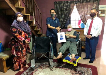 HISHAMUDDIN Abdul Rahim (dua kiri) menyampaikan bantuan kerusi roda dan wang saguhati daripada YRZSNJ kepada Azlina Mohd. Rawi di Taman Sentosa di Kluang Johor. –UTUSAN/NUR NABILAH RAHMAT