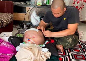 MUHAMMAD Azhar Arzemi sedang mencuci kepala Muhammad Bilal Yusra di rumahnya di Kampung Sungai Ular, Kulim, hari ini. - UTUSAN/AZHAR HASHIM