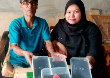 ROSLAN Bakar bersama Rabiatul Adawiyah menunjukkan dodol lemak yang dijual secara dalam talian di Jalan Datuk Kumbar, Alor Setar, Kedah. - UTUSAN/JAMLIAH ABDULLAH